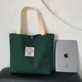 Dark green canvas tote bag with lovable dog patch and white handles next to an iPad - Dark Green