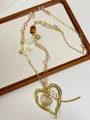 Gedetailleerde macro-opname van vintage gouden hartvormige hanger en lange halsketting - Gouden Hart Strik Rode Edelsteen Stijl