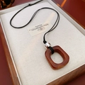 Vue macro détaillée du pendentif en résine ambrée dans une boîte à bijoux en bois - Carré Irrégulier (Café-Argent) / Café-Argent