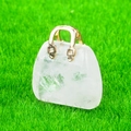 Mini handbag-shaped white crystal pendant with golden metal handle on green grass - White Crystal
