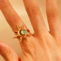 Golden sunburst ring featuring a central green gemstone on a model hand - 18k Gold Plated (12305)