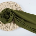 Lightweight olive green chiffon hijab scarf with soft drapes on a rustic woven mat - 101