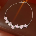 Macro shot of silver flower necklace with seven pink gems on brown leather surface - Pink Flower Necklace (WN1546-1)
