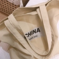 Primer plano del bolso tote de lona beige con estampado de letras CHINA BOUNCE BACK - Caqui
