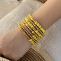 Detailed view of layered bohemian beaded bracelets in vibrant yellow and gold tones - Yellow