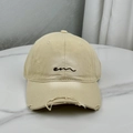 Detailed close-up of distressed cotton baseball cap with black embroidered lettering - Beige