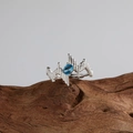 Dettaglio dell'anello in argento S925 con topazio blu su un blocco di legno naturale - Anello in argento con topazio naturale