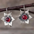 Gros plan de boucles d'oreilles vintage en argent avec pierre rouge sur branche - Boucles d'oreilles / Rouge