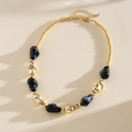 Dettaglio della collana alla moda con perle acriliche irregolari dorate e nere su sfondo - Nero