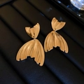 Detalle de pendientes de cola de pez dorados con textura metálica y diseño articulado - Dorado