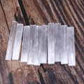 Natural selenite crystal sticks arranged neatly on dark wood for home decor display - Selenite Wand