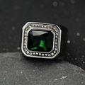 Macro di un anello con gemma verde taglio smeraldo e halo di diamanti su fascia larga - Acciaio + Pietra Verde