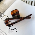 Detailansicht einer bernsteinfarbenen Haarklammer mit glänzendem Kreuzkurven-Design - Schmetterlingsschnalle Band (ca. 12cm) / Glänzend Rotbraun
