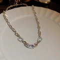 Gros plan de la chaîne géométrique argentée avec zircons sur une assiette blanche - Collier Chaîne de Zircone Argenté