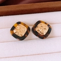 Macro view of vintage tiger eye style earrings in 18k gold plating on beige velvet - Tortoise