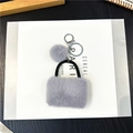 Dettaglio portachiavi a borsa in peluche grigia con chiusura argentata e pompon in pelliccia - Confezione in busta singola OPP / Grigio