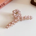Detailopname van roze bloemen haarklem met witte parels op een beige achtergrond - Roze Bloem Parel