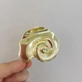 Vista detallada de pinza para el pelo con forma de concha dorada y textura de espiral - Dorado