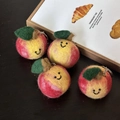 Set of four handmade red wool felt apple keychains with cute smiles on wood background - Peach Collection
