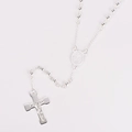 Détail du collier à billes argentées avec pendentif crucifix et médaille sur fond blanc - Argent