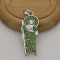 Close-up of silver religious pendant with green rhinestones on a wooden display - Silver + Green Zirconia