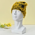 Detail of yellow and black knit beanie featuring long fluffy fringe textures on a mannequin - Yellow