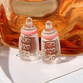 Detail of two miniature resin baby bottles with pink rings and molded scale markings - Pink