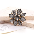 Detail view of flower-shaped zinc alloy crystal charm on a textured stone surface - Gray