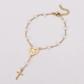 Vista dettagliata del bracciale di perle dorate con medaglione cuore e ciondolo a croce - Bianco