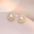 Macro shot of gold oval stud earrings with radiant zircons on champagne silk - Golden Oval Radiant Style (E0779)