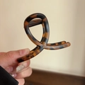 Macro shot of large amber acetate hair claw clip showing elegant tortoiseshell pattern - Small Brown Tortoiseshell Cross Claw Clip