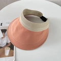 Detail of orange-pink sun visor hat with adjustable strap on a white table background - Orange