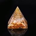 Orgone pyramid featuring orange crystals, copper coil, and gold leaf in resin - Sunstone