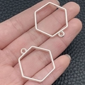 Pair of silver hexagonal alloy hollow frames for DIY jewelry pendants in hand - Hexagon Bezel (22252) / 29x28mm / Bright Silver