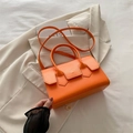 Chic bright orange faux leather handbag on a beige blazer, single shoulder strap style - Orange