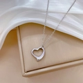 Detalle de un colgante de corazón plateado sobre un joyero y tela de seda suave - Plateado