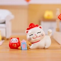 Miniature resin Fortune Cat, red Daruma, and blue lucky charm on a wooden surface - -263 Receiving Blessings