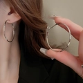 Detailed view of large silver hoop earrings worn by a model and held for macro texture - Steel Earring Post Large Hoop Style (23#)