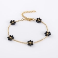 Close-up of golden link bracelet featuring six handmade black beaded flower charms - Black
