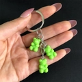 Dettaglio di un portachiavi in metallo argento con tre ciondoli a forma di orsetto verde - Verde
