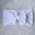 Detail of white nylon baby headband featuring a large bow and cable knit texture - White