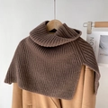 Donkerbruine grofgebreide coltruiponcho op een camelkleurige jas voor een winterse look - Bruin