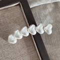 Dettaglio del fermaglio per capelli con cuori bianco crema e lucentezza perlata su vassoio - Clip Cuore Curva - Bianco