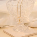 Detail van een gouden bloem hanger ketting met zirkoon bloemblaadjes op stenen basis - Wit