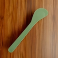Olive green plastic face mask mixing spatula tool on dark wood grain background - Solid Green