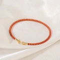 Detail of red and gold woven bracelet featuring polished spherical metal end caps - Red Gold