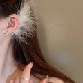 Macro shot of a silver feather ear cuff with rhinestone bows worn on a model - Bowknot Feather Ear Hook Left (HE16172)