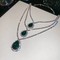 Dettaglio di tre ciondoli a goccia di smeraldo con pavé di diamanti su una catena tennis - Collana-Verde-Goccia