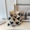 Close-up of beige knitted tote bag with black heart patterns and fine woven texture - White