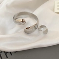 Macro shot of polished silver oval open cuff and ring set on elegant white satin fabric - Irregular Wide Mirror Set / Silver